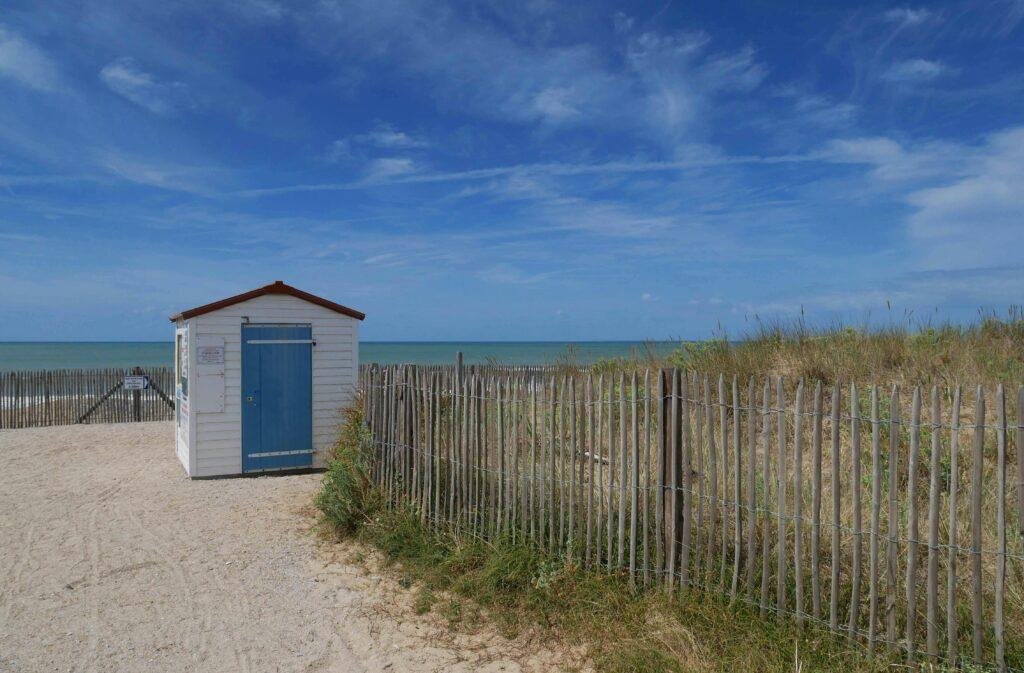 Cabane blanche et bleue sur la plage de St Hilaire de Riez, entre sable et océan, symbole du littoral vendéen et de la douceur de vivre